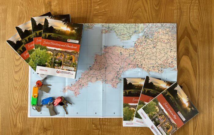 Caravan and Motorhome Club. Campsite+ image of map and book on a table.